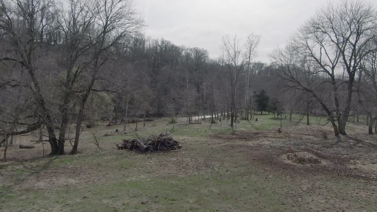 low altitude aerial view past a burn pile by the river