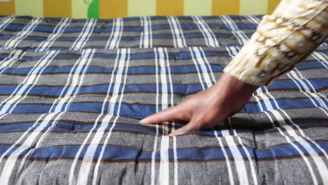 a person's hand pressing on a plaid mattress