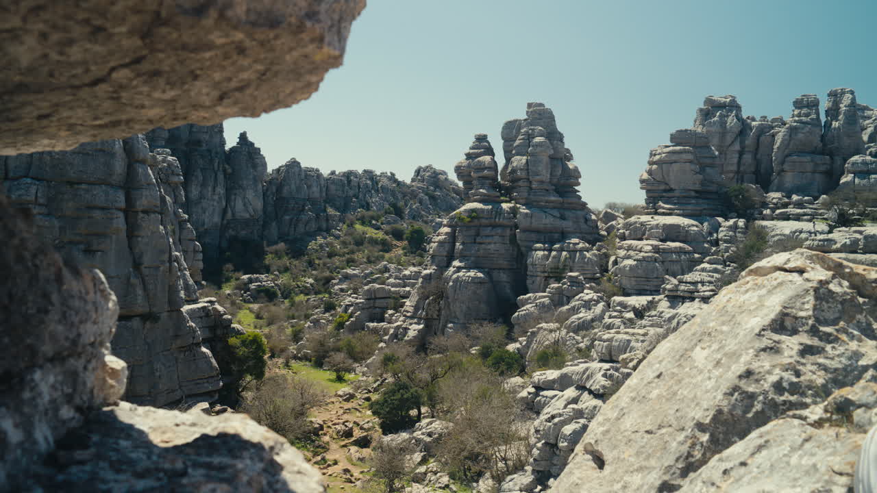 Kaunis laakso, jota kehystävät kalkkikivimuodostelmat El Torcal de Antequerassa, Espanjassa, esitellen dramaattista karstimaastoa, kerroksellista geologiaa ja luonnollisia tekstuureja kirkkaassa päivänvalossa.