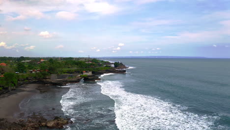 Rocky-coastline-of-Bali-with-houses-and-foamy-sea-waves,-Indonesia