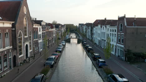 dutch buildings and parked cars along turfmarkt canal in gouda, netherlands