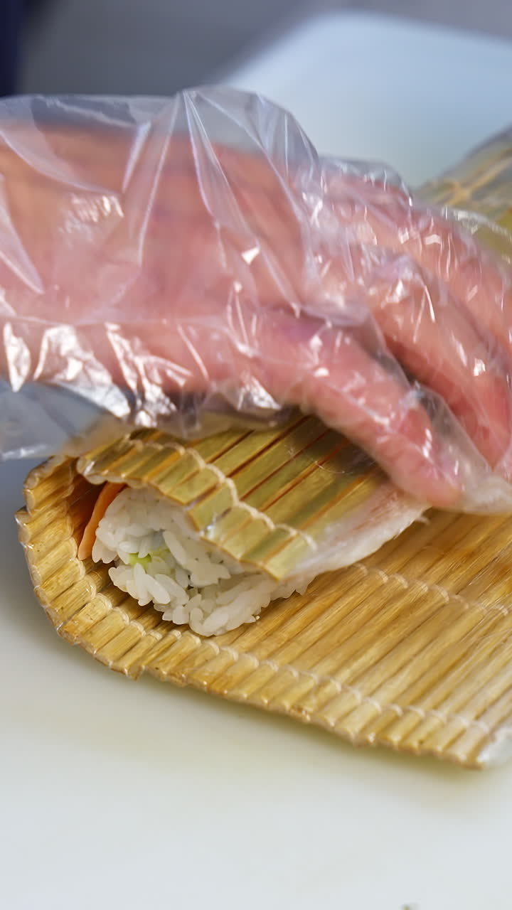 Chef hands preparing japanese food. Close up view of preparation of sushi roll in restaurant. Vertical video
