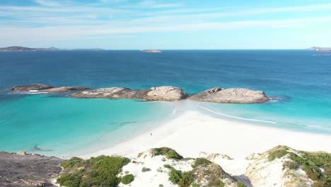 Excelente-Toma-Aérea-De-Un-Turista-Trotando-En-La-Playa-Blanca-Junto-Al-Agua-Azul-Clara-En-Wylie-Bay,-Esperance,-Australia