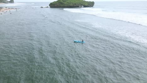 aerial orbit drone shot of a man was paddling a canoe with an oar in the middle of the beach