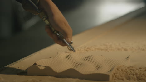 a person blows wood chips off a piece of wood