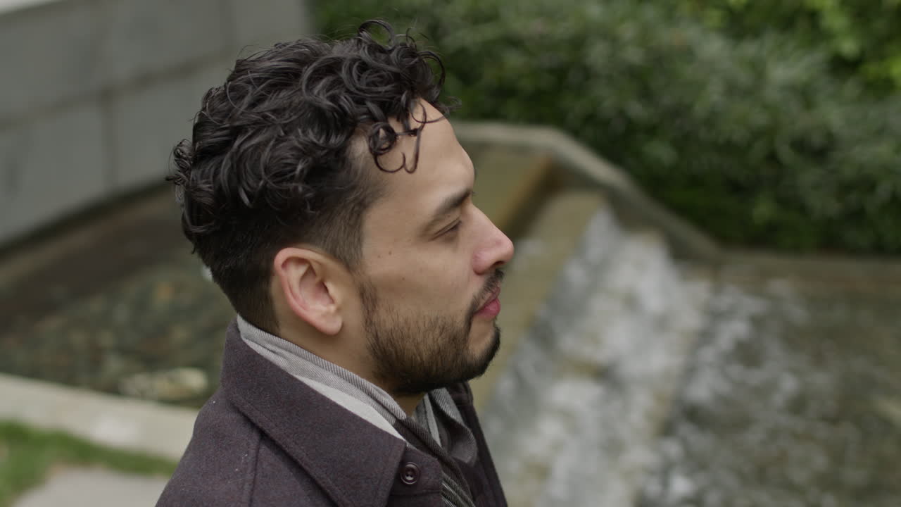 hombre guapo de mediana edad sentado en el parque junto al agua solo, pensando contemplando la vida