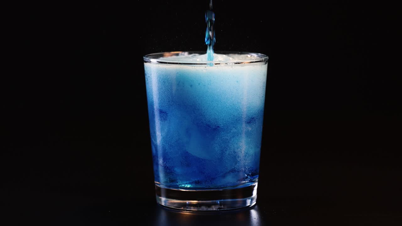 Blue drink poured, creating bubbles and foam