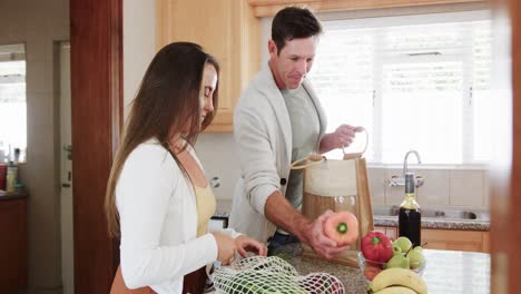 Feliz-Pareja-Caucásica-Desempacando-Compras-Juntos-En-La-Cocina,-Cámara-Lenta