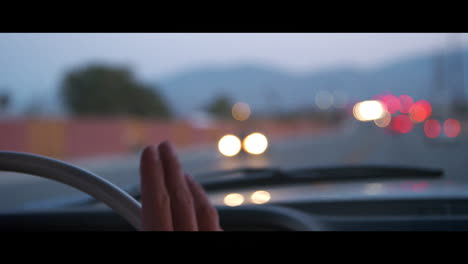 hombre tocando el volante mientras conduce, con luces bokeh