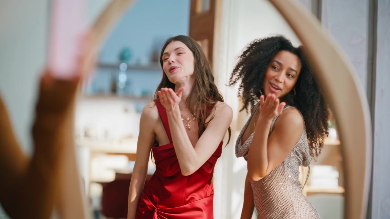 Donne eleganti che ammirano il riflesso nello specchio indossando abiti. Una mora che scatta foto.