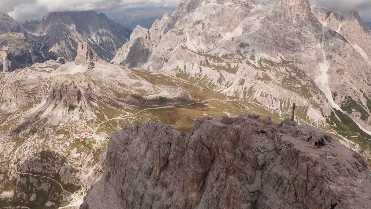 toma aérea hacia atrás sobre el pico de la montaña monte paterno con cruz y hermoso paisaje durante el verano - mar en el valle en dolomitas, italia