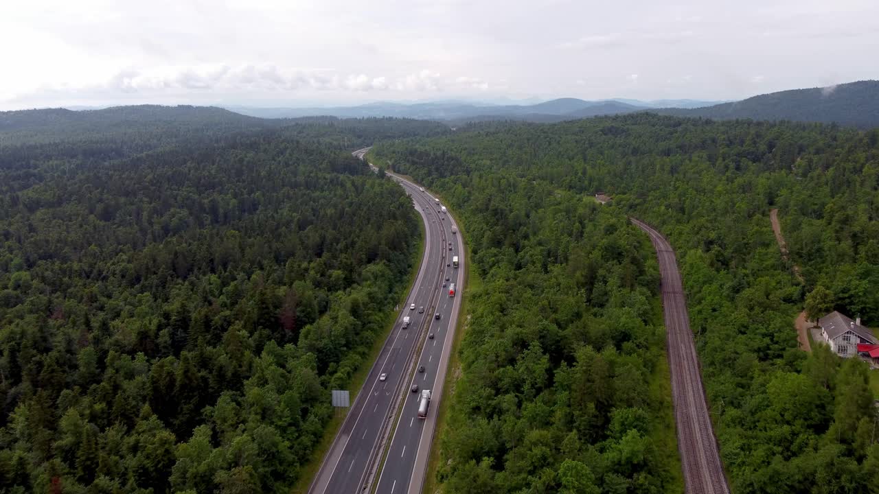 autopista europea de 2 carriles con buen flujo de tráfico y ferrocarril y rieles justo al lado y cinturón verde que rodea la carretera nacional