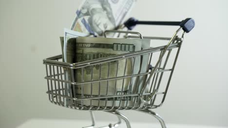 Carrito-De-Compras-Con-Nota-De-Billetes-De-100-Dólares-Sobre-Fondo-Blanco-Estrategia-De-Marketing-Exitosa-En-Línea-De-Venta-De-Comercio-Electrónico