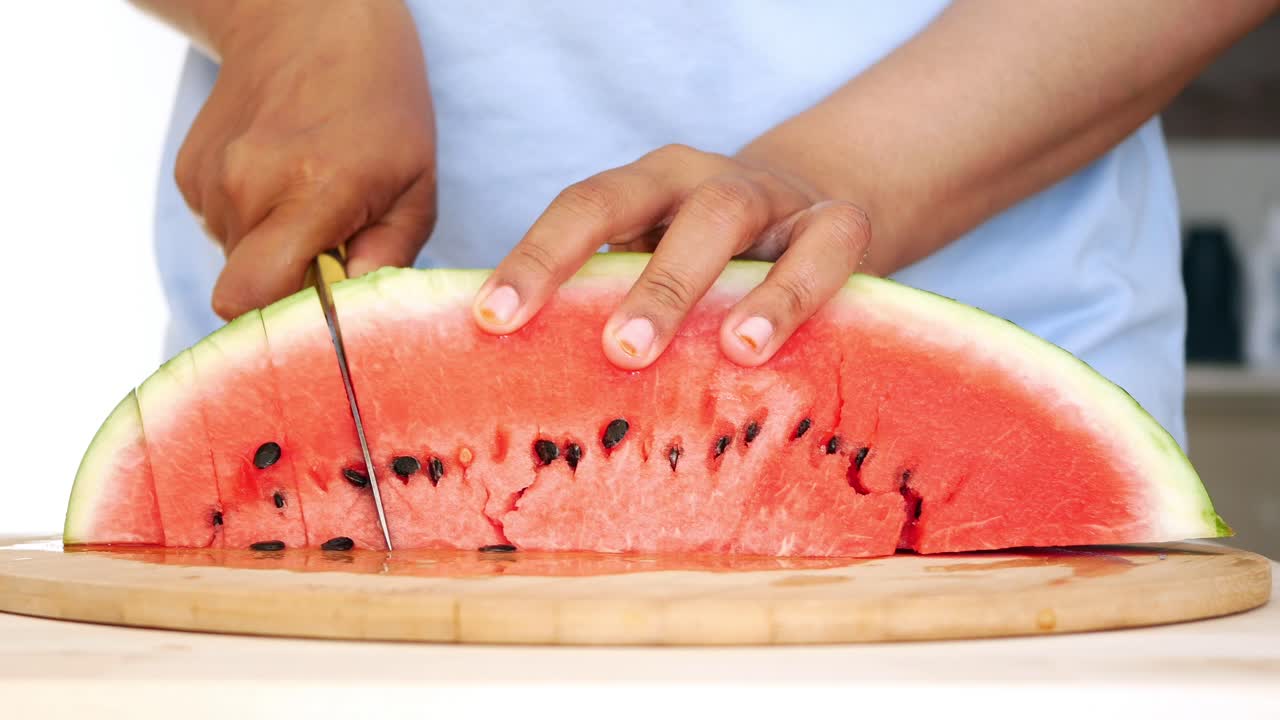 una mujer cortando una sandía.