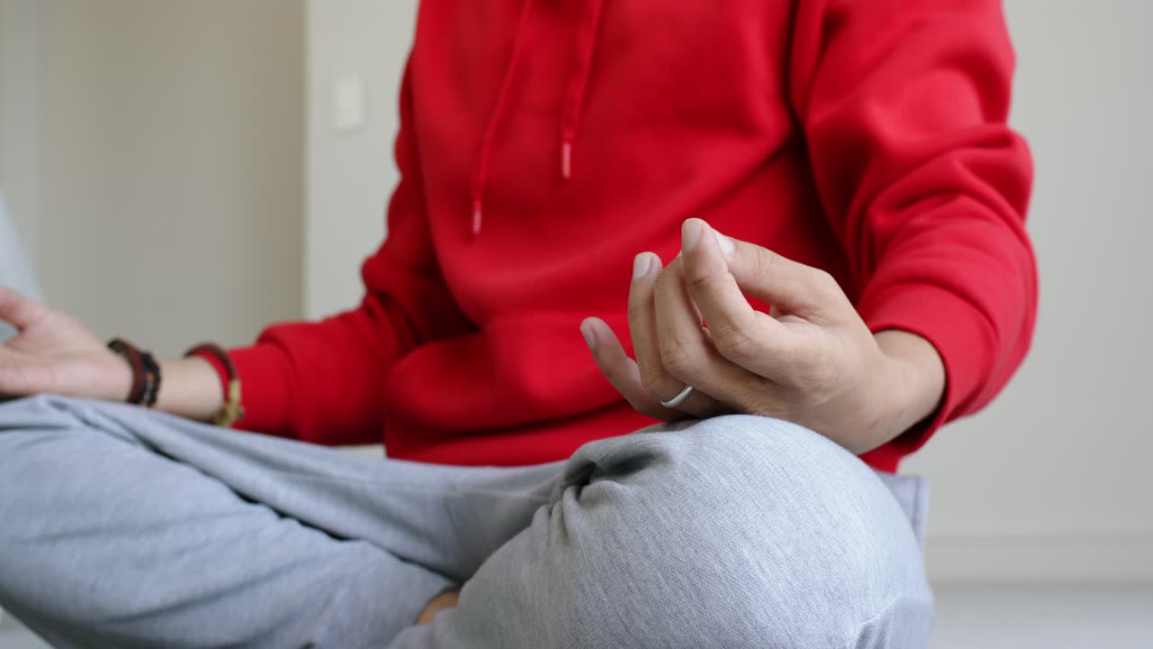 Kamera, yeşil mat üzerinde bağdaş kurmuş şekilde oturan ve sakinleşmek için nefes alan bir meditasyoncuyu kaydetmeye başlıyor