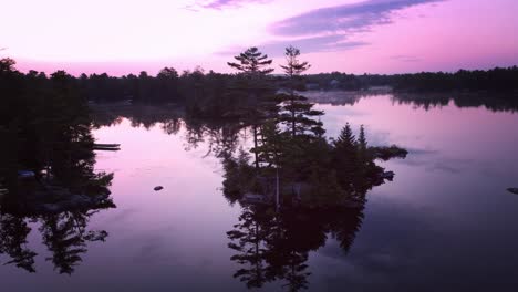 island silhouette reflected on calm ontario lake in morning twilight