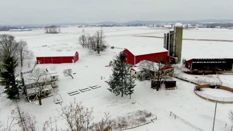 aerial truck shot reveals red farm buildings against white snow