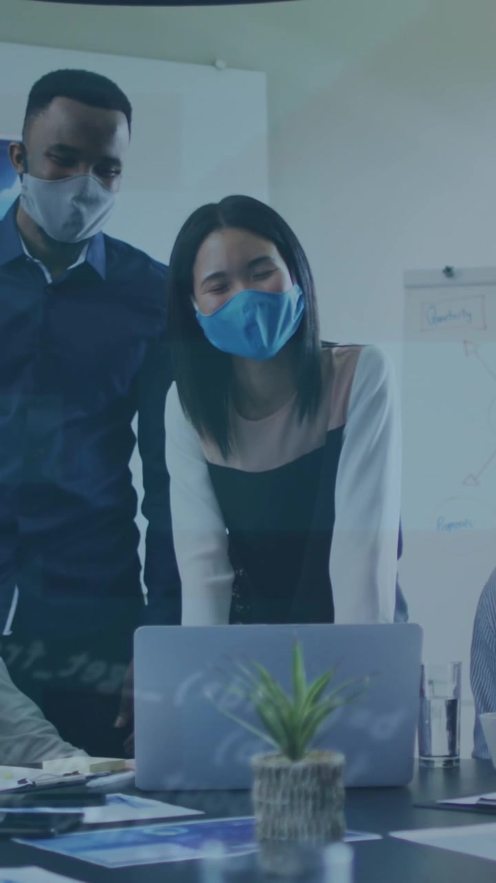 Animation of data processing over diverse business people with face masks using laptop