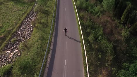 Hombre-Patinando-Sobre-Ruedas-En-Una-Carretera-Vacía,-Puesta-De-Sol,-Toma-Aérea-Cinematográfica