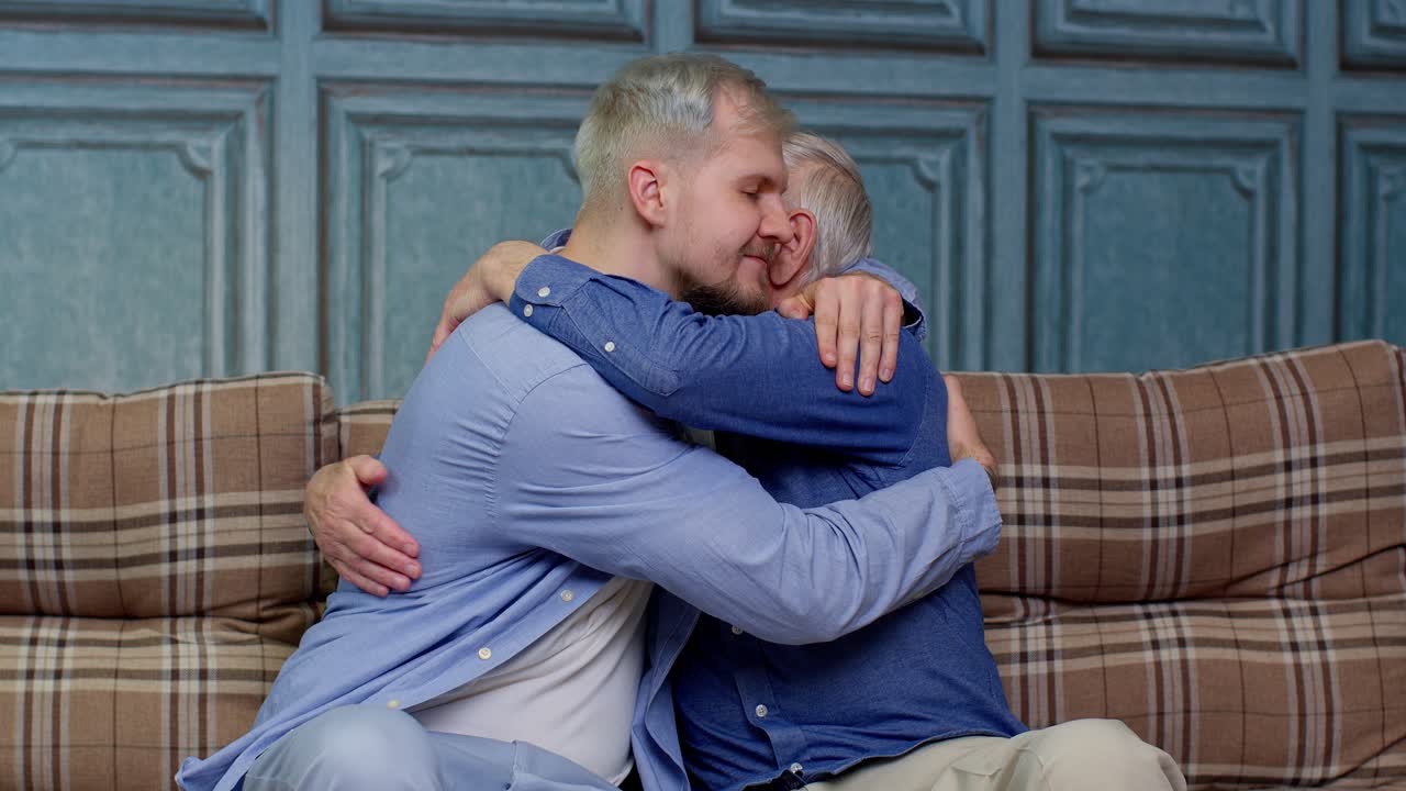Giovane uomo gioioso ed entusiasta che abbraccia il padre o il nonno anziano dai capelli grigi, famiglia di generazioni maschili