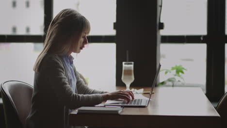 mixed race woman working from home on laptop computer. asian lady is using laptop at home typing then taking notes in notebook