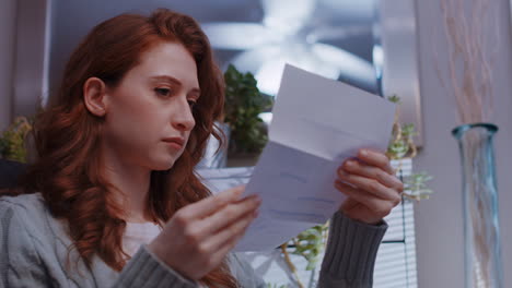 a young caucasian woman opens a letter and reads it