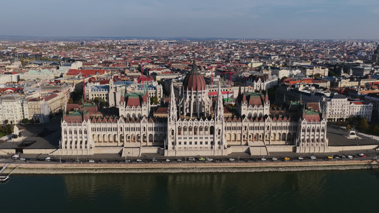 Panorama aereo del Parlamento ungherese lungo il Danubio, incorniciato da edifici storici e dallo vasto skyline di Budapest