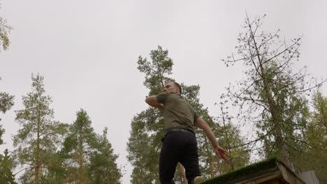 low angle of disc golfer throwing a backhand throw from elevated tee - full shot