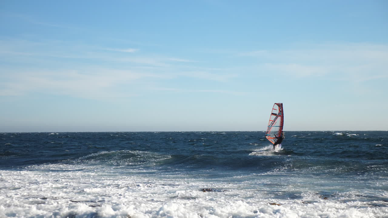 toma panorámica de un windsurfista noruego que cambia de dirección, mientras navega en el mar del norte, en el océano atlántico, en un día soleado de verano, en lista, sur de noruega