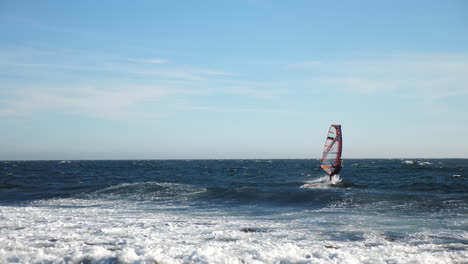 pan shot of a norwegian windsurfer changing direction, while sailing on the north sea, in the atlantic ocean, on a sunny, summer day, in lista, south norway