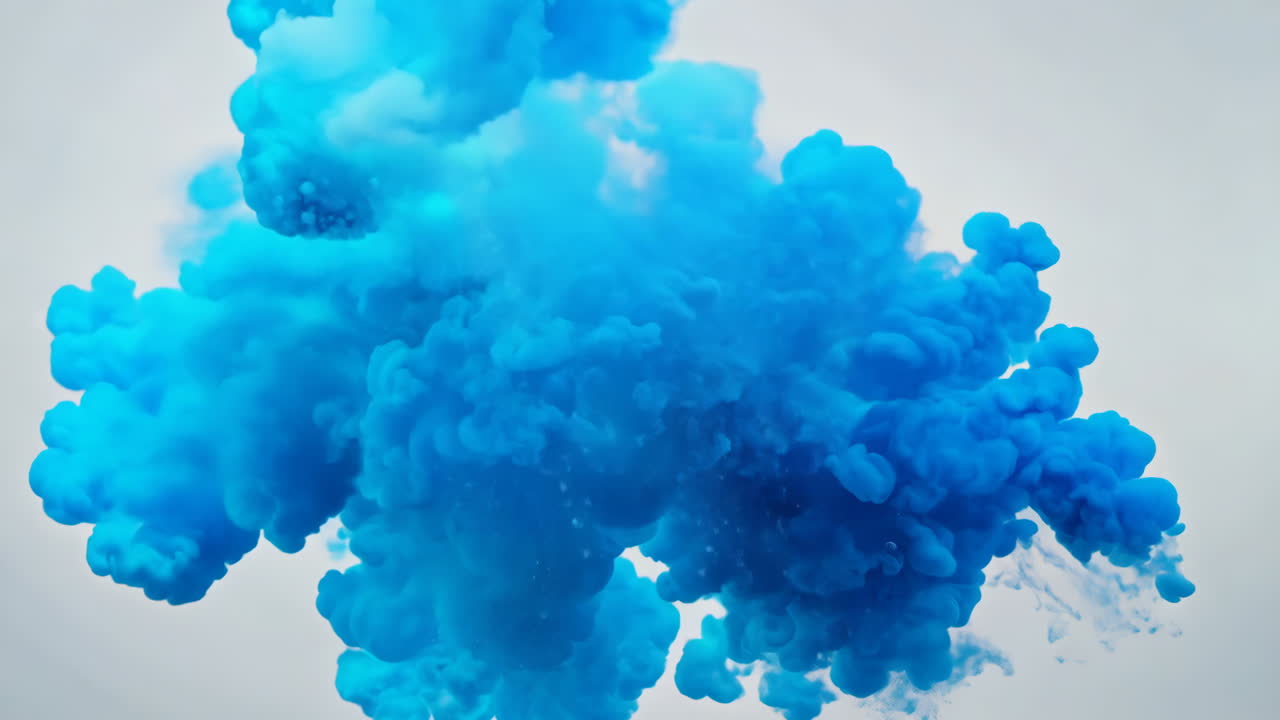 Blue Smoke Cloud During Daytime Outdoor Event. A vibrant blue smoke cloud rises into the sky, creating a striking visual effect during an outdoor activity.