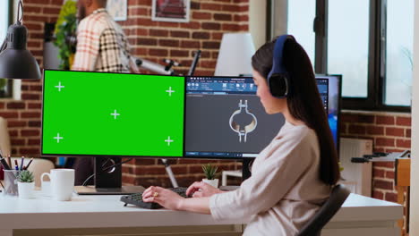 Software-developer-works-in-a-modern-office-with-green-screen-and-dual-monitors