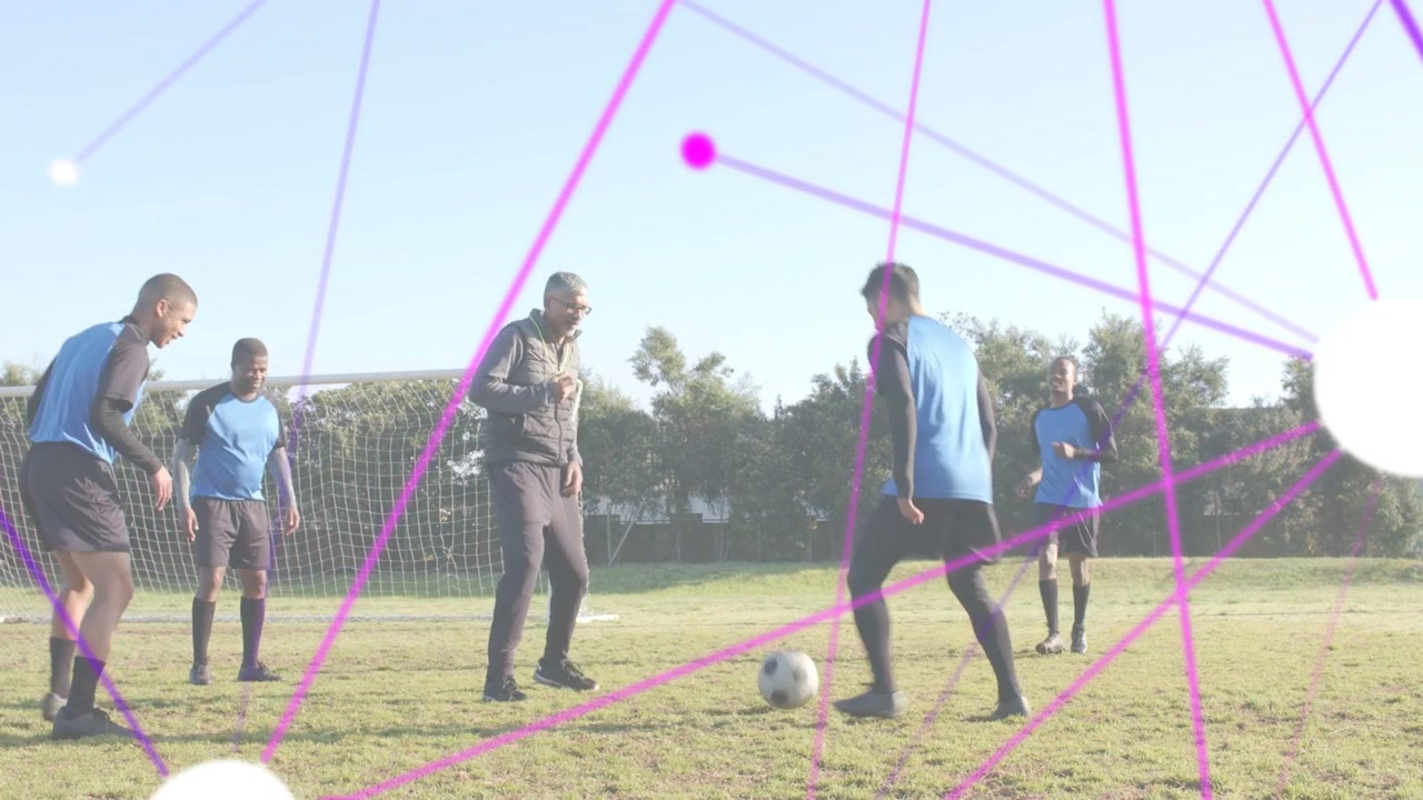 Trener snakker og gestikulerer, lag som pasningsspiller i fotballøvelse nær et miniatyrmål, med et kryssende magenta overlegg
