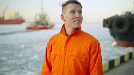 Hafenarbeiter-In-Orangefarbener-Uniform-Mit-Blick-Auf-Das-Meer-Und-Genießen-Die-Landschaft-Des-Hafens-Im-Winter.-Vereistes-Meer