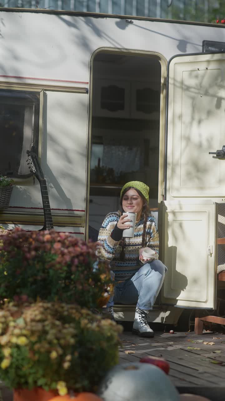 mujer disfrutando de un descanso de café en un remolque de campamento en un día de otoño
