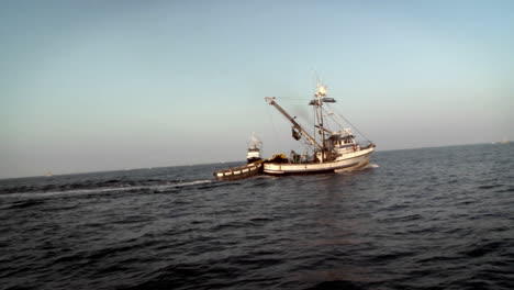 a boat with a dinghy sails through the water