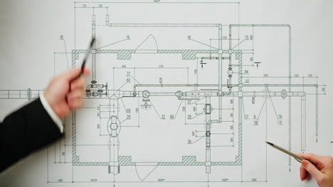 people's hands pointing at a technical engineering blueprint
