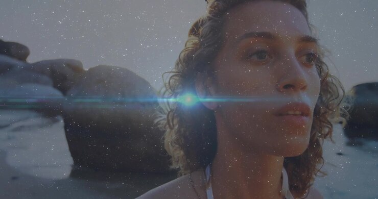 Woman pivoting on shore at sunset digital specks drifting left causing lens flare for advertising