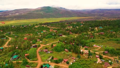 Aerial-Drone-View-of-Mountain-Homes-Surrounded-by-Pine-Trees-and-Colorado-Rocky-Mountain-Peaks-on-a-Cloudy-Summer-Day