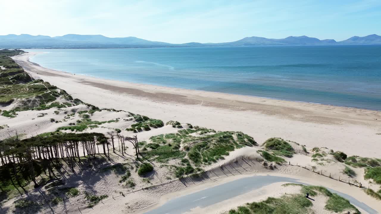 Newborough beach aerial view above sunny woodland car park coastline and Snowdonia mountain range