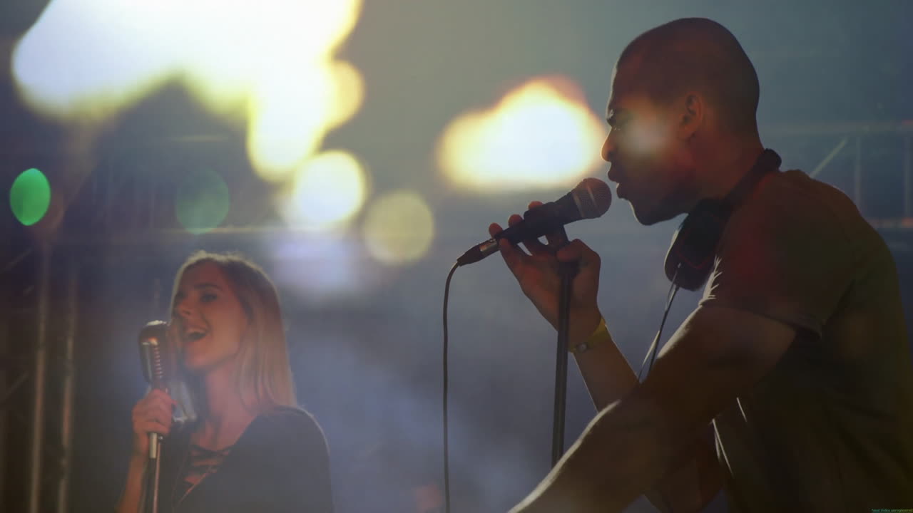 Bandmates performing on smoky concert stage, displaying animated sound waves over microphones