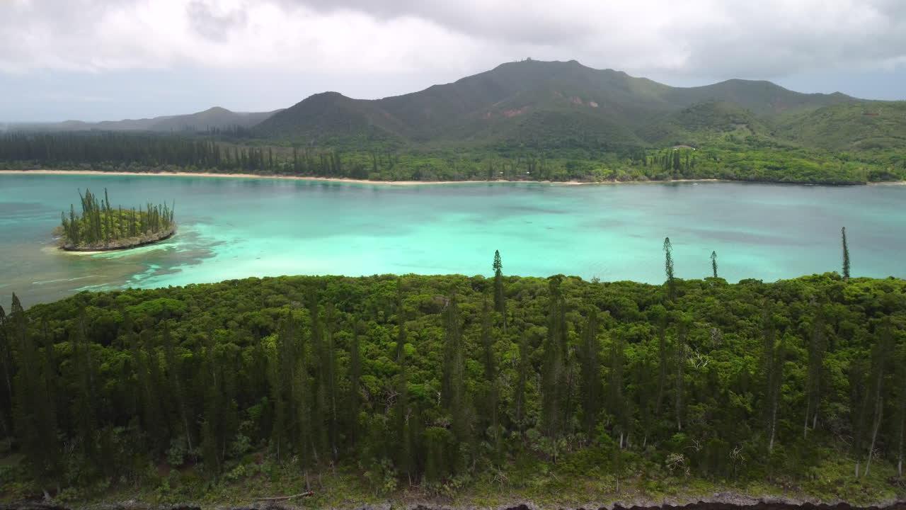 toma aérea ascendente que revela pinos columnares, agua cristalina y pico n'ga, isla de pinos