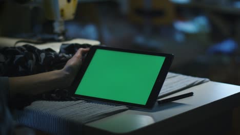 la costurera está sosteniendo una tableta con una pantalla de maqueta en modo paisaje.