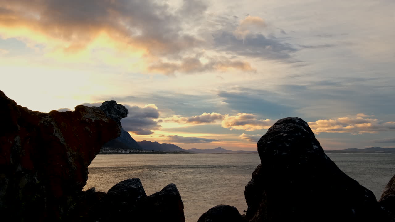 Silhouette of rock formations on Hermanus coastline overlooking ocean at sunrise