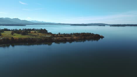 lago chiemsee en baviera, alemania con el dolor del delta tiroler del río en otoño con agua azul y cielo, árboles en una isla y horizonte con los alpes alemanes y austriacos en el fondo