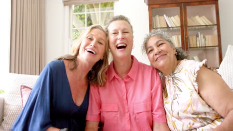 three joyful senior women share a close moment at home