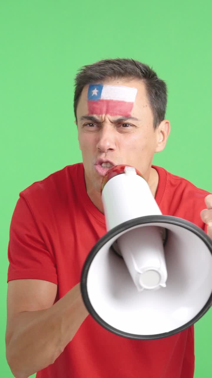 Excited man with chilean flag on face using a megaphone