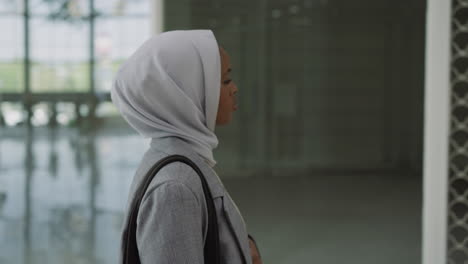 una joven negra con hijab mira alrededor en un centro comercial