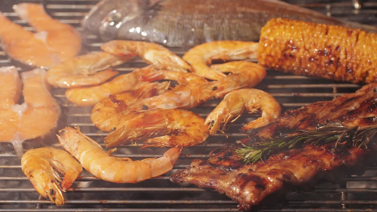 Chef cooking red salmon fish steaks with oil and spices on grill close-up. Prawns on fire throwing them on pan. Making Dorado fishes on frying grill. Restaurant Food concept. Sea food barbecue.