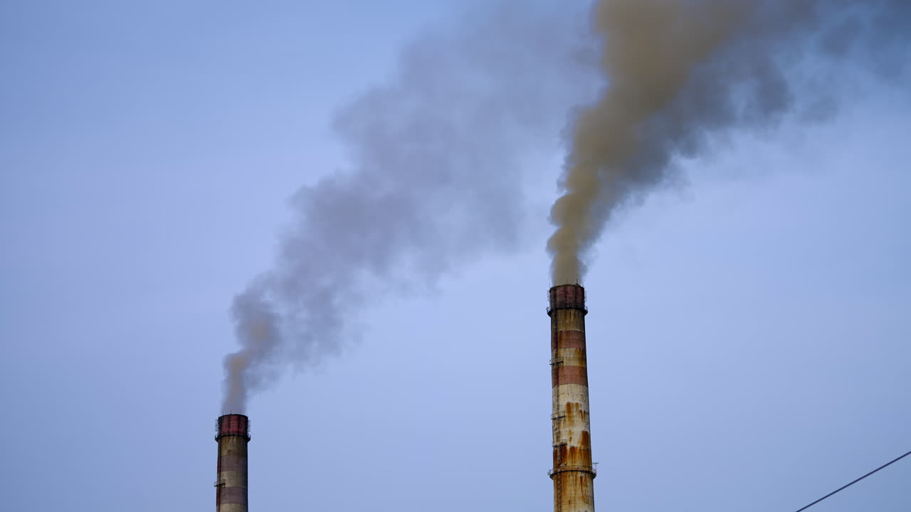Smoke pouring from two industrial pipes. Factory cocncrete pipes pollute air with smoke.